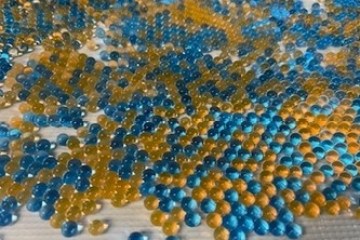 Scattered blue and orange beads on a textured white surface.