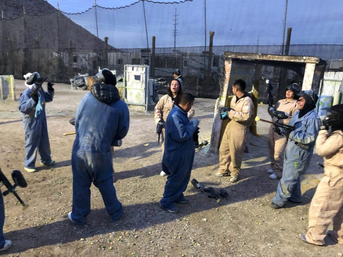 Group of people in protective gear with paintball guns on an outdoor field.